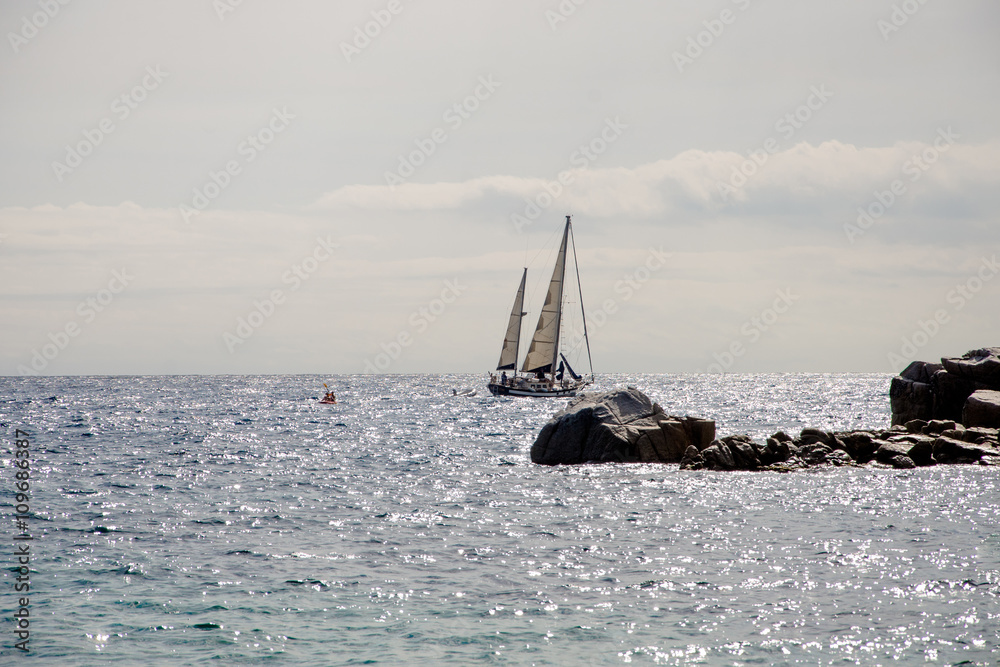 Boat in the sea and rocks in the Bay of Tossa de Mar, Spain