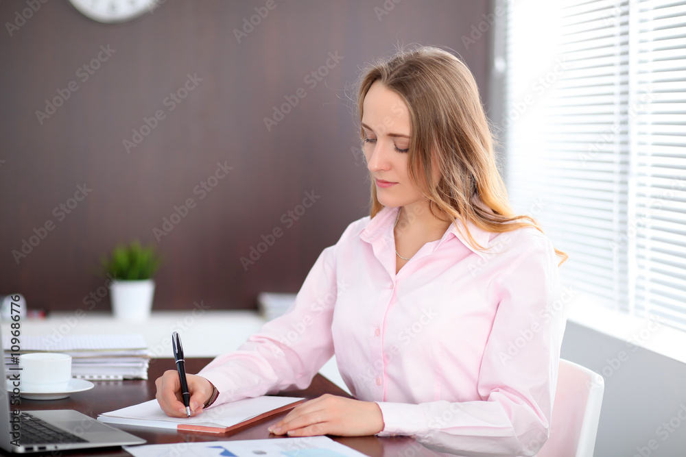 Young business woman sitting at the table in the office Young business woman sitting at the table in the office