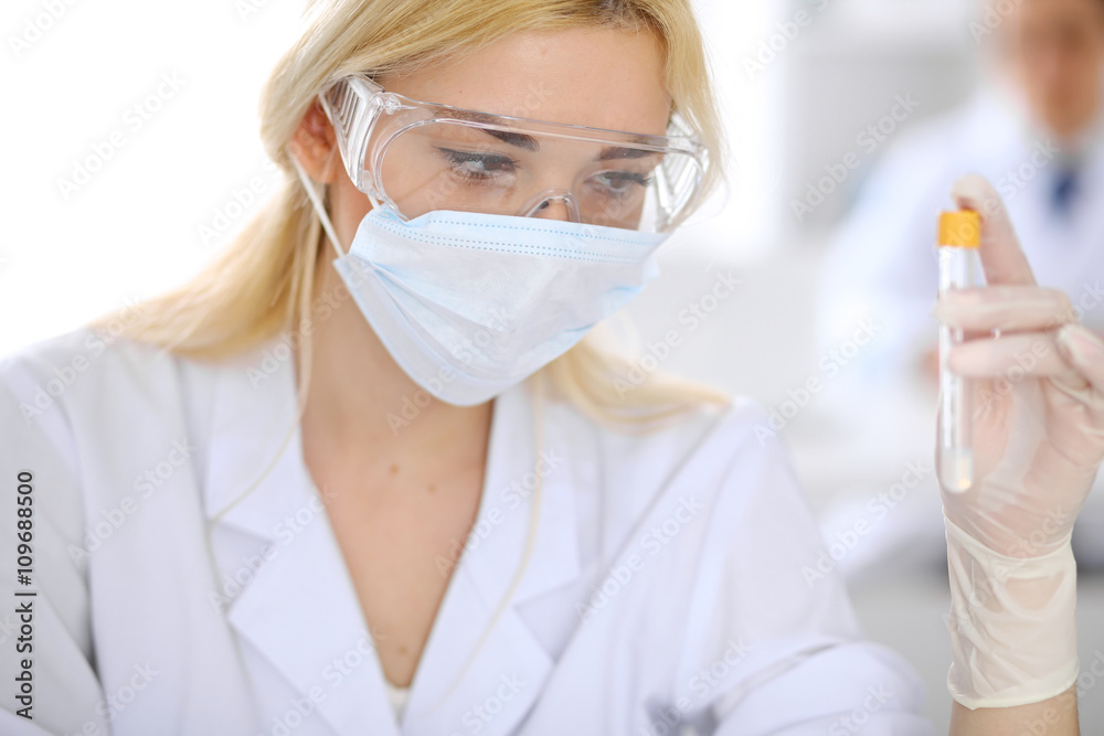Female scientific research team with clear solution in laboratory Female scientific research team with clear solution in laboratory