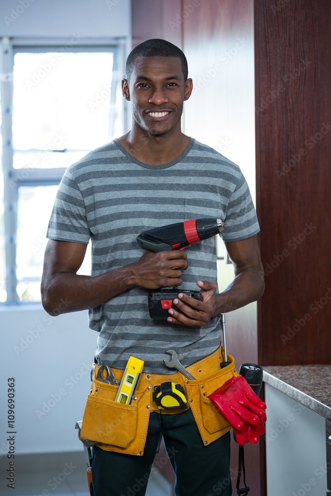 Smiling manual worker holding a drill machine Smiling manual worker holding a drill machine