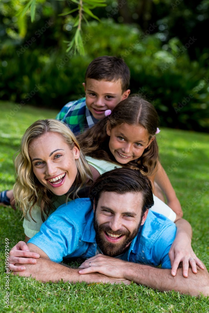 Smiling family lying on top of each other in yard Smiling family lying on top of each other in yard