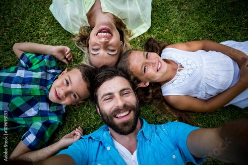 Cheerful family lying on grass in yard 
