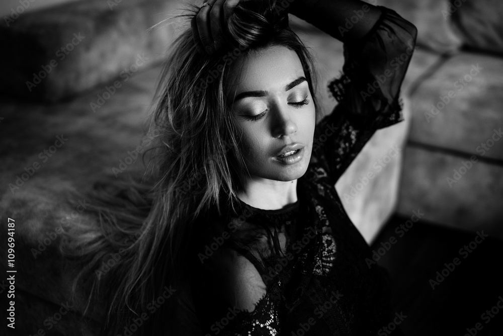 Black and white art photo. Beautiful, sexy, elegant woman with long blond hair posing in a black lace dress with make-up and hair style at home Black and white art photo. Beautiful, sexy, elegant woman with long blond hair posing in a black lace dress with make-up and hair style at home