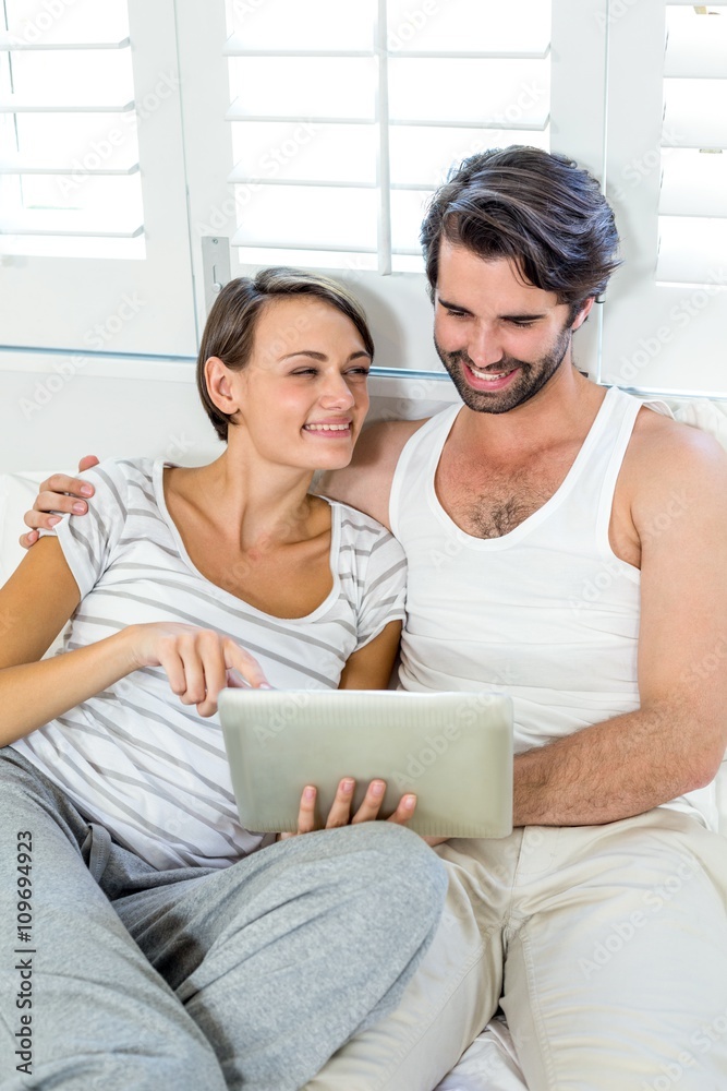 Smiling couple using digital tablet on bed Smiling couple using digital tablet on bed