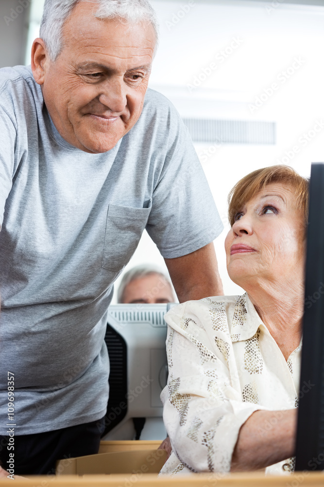 Senior Man Assisting Woman In Computer Class Senior Man Assisting Woman In Computer Class