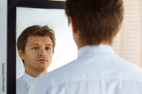 Portrait of unsure young businessman with unhappy face