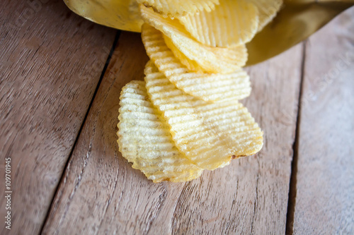 Opened pack with potato chips over wooden table