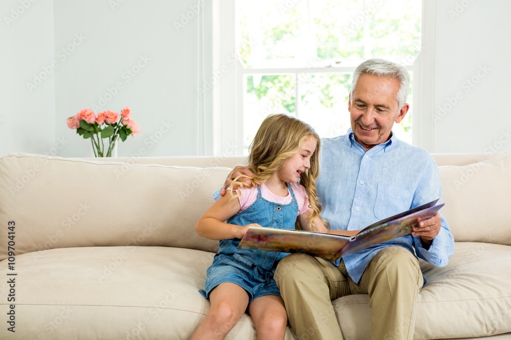 Smiling girl and granddad with picture book