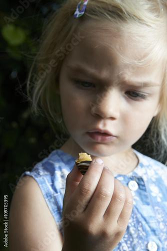 little young beautiful girl holding small snail in hand