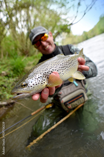 Fototapeta Naklejka Na Ścianę i Meble -  Happy fly-fisherman holding fario trout