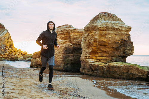 Running man. Male runner jogging during the sunrise on beach.