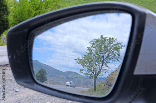 reflection of the mountain road in a car rear-view mirror