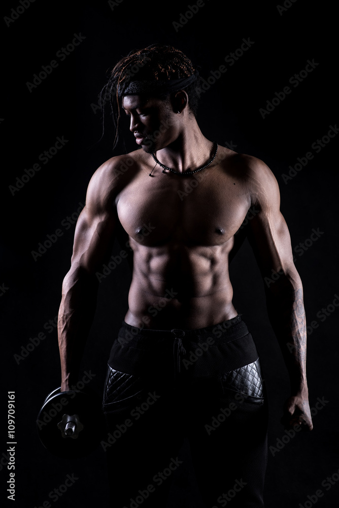  Male fitness model showing muscles in studio with a black background