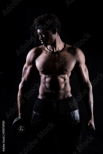  Male fitness model showing muscles in studio with a black background