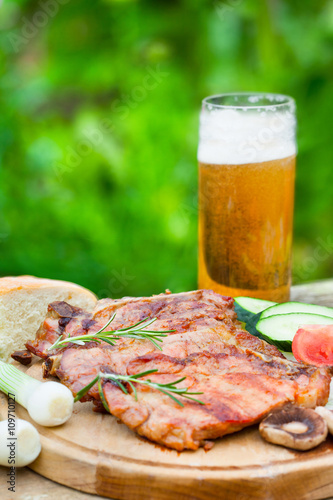  Grilled meat served on wooden board with glass of beer 