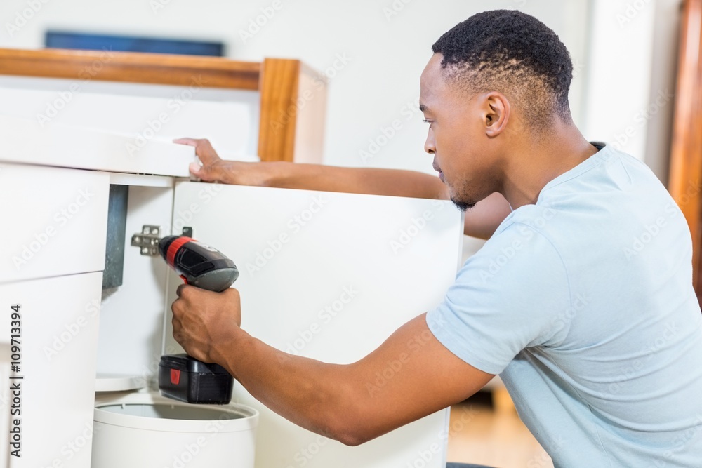 Man drilling a hole inside the cabinet Man drilling a hole inside the cabinet