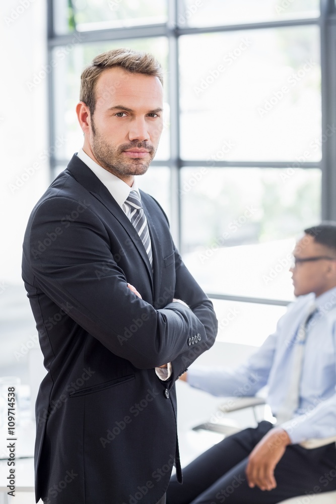 Happy businessman standing with arms crossed