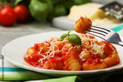 Serving gnocchi in tomato sauce with cheese.