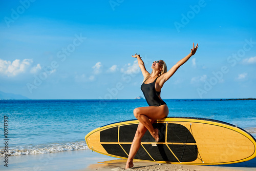 Healthy fit beautiful surfer woman in bikini and sunglasses enjo