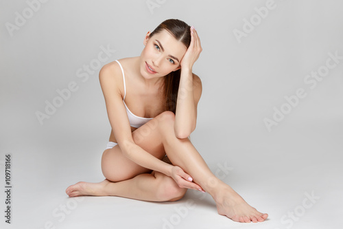 Slim tanned woman's body over gray background