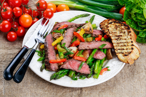 Grilled steak with stir-fried vegetables on plate.
