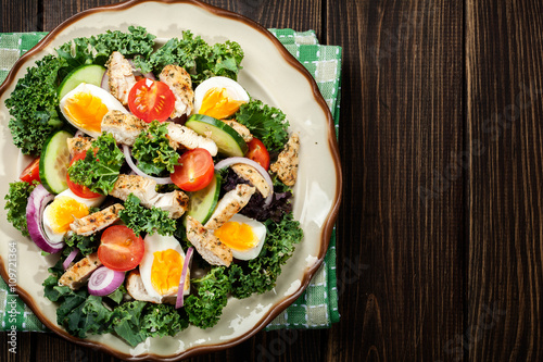 Fresh salad with chicken, tomatoes, eggs and lettuce on plate