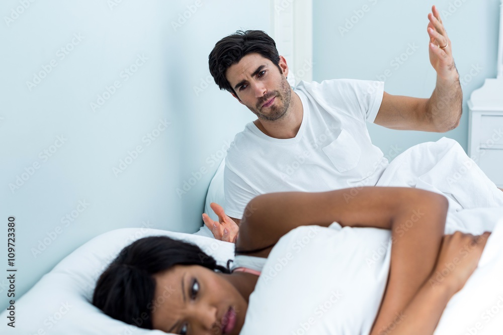 Obraz premium Young couple arguing on bed in bedroom