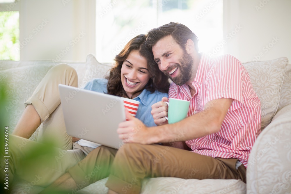 Couple sitting on sofa and using laptop Couple sitting on sofa and using laptop