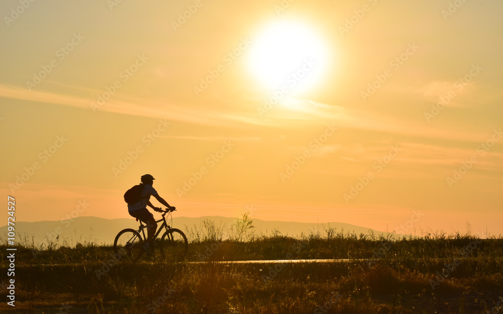 Cyclist on sunset sky with clouds