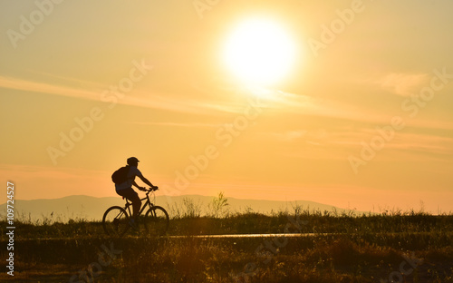Cyclist on sunset sky with clouds © oralz