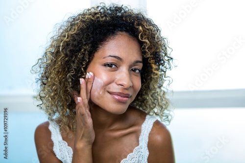 Young woman applying moisturizer photo