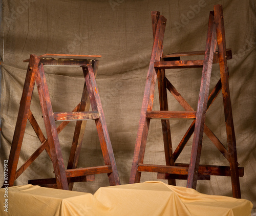 Vintage rustic handmade ladders in front of a hessian sack draped brown textured backdrop. photo