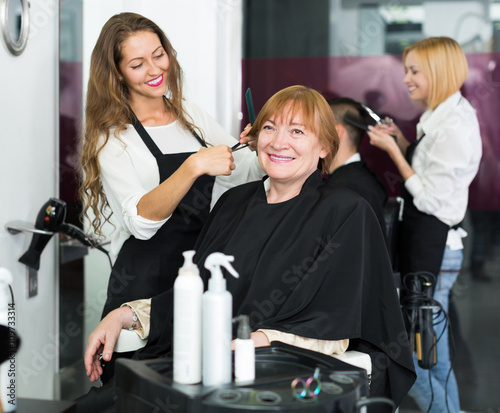 Mature woman cuts hair with barber