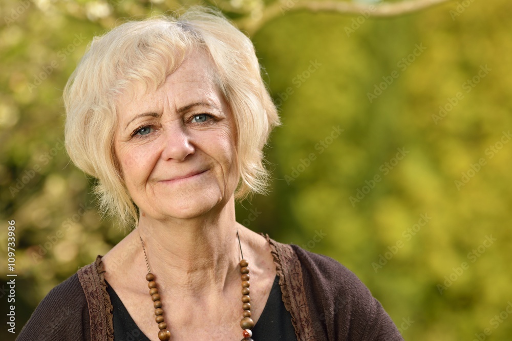 Mature, blonde woman in garden.