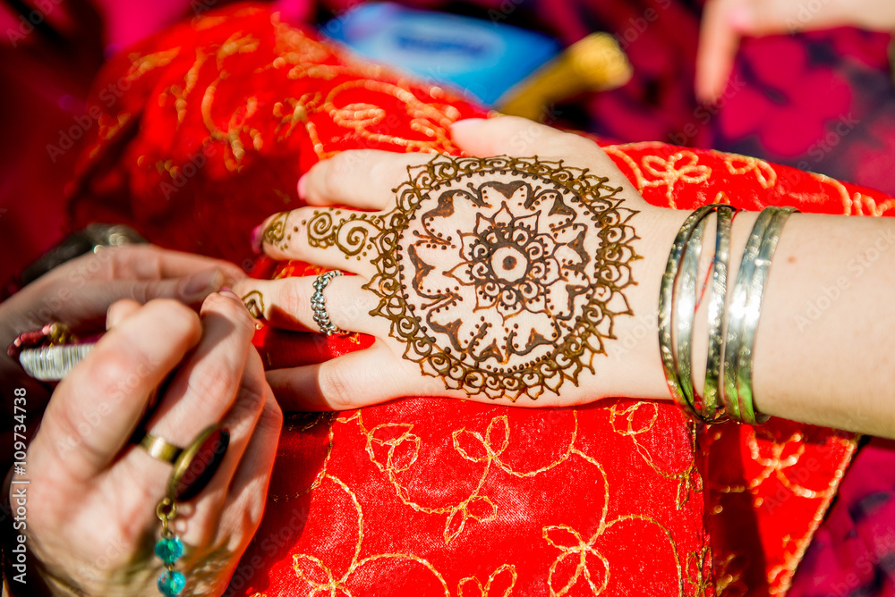 Fototapeta premium Picture of human hand being decorated with henna tattoo, mehendi