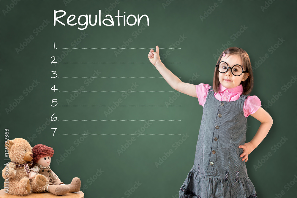 Φωτογραφία Cute little girl wearing business dress and showing blank regulation list on green chalk board