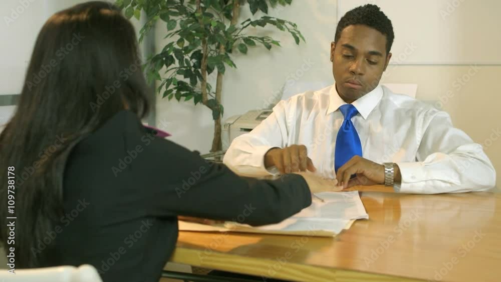 A man sitting across from a pretty businesswoman shakes her hand after signing a legal document she was explaining to him. A man sitting across from a pretty businesswoman shakes her hand after signing a legal document she was explaining to him.
