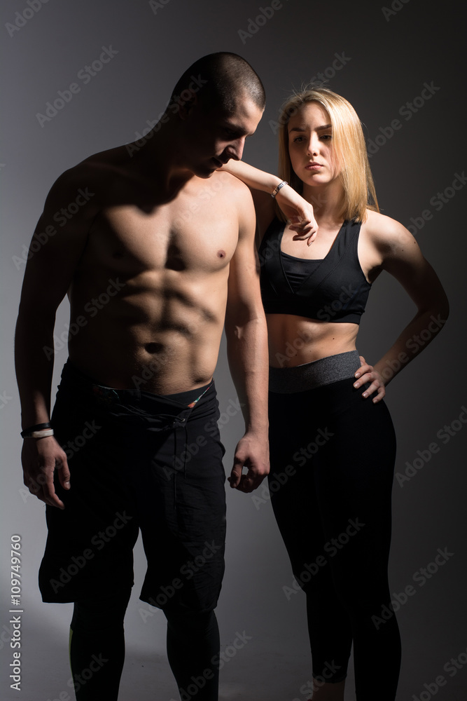 Man with a naked torso and a girl. Athletes on a dark background in the studio Man with a naked torso and a girl. Athletes on a dark background in the studio