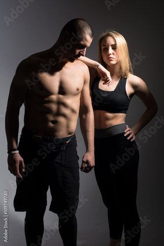 Man with a naked torso and a girl. Athletes on a dark background in the studio