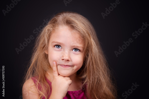 Little cute pensive girl in a bright pink dress