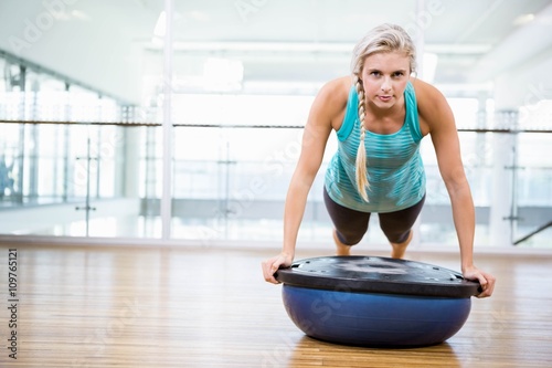 Fit blonde doing push up on bosu ball