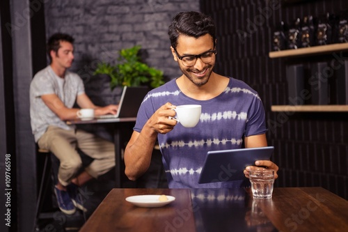 Man using a tablet and drinking coffee