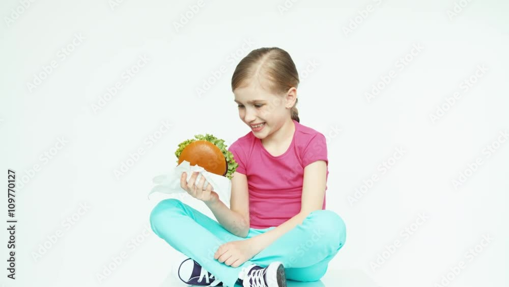 Girl 7-8 years holding burger. Thumb up. Ok Girl 7-8 years holding burger. Thumb up. Ok