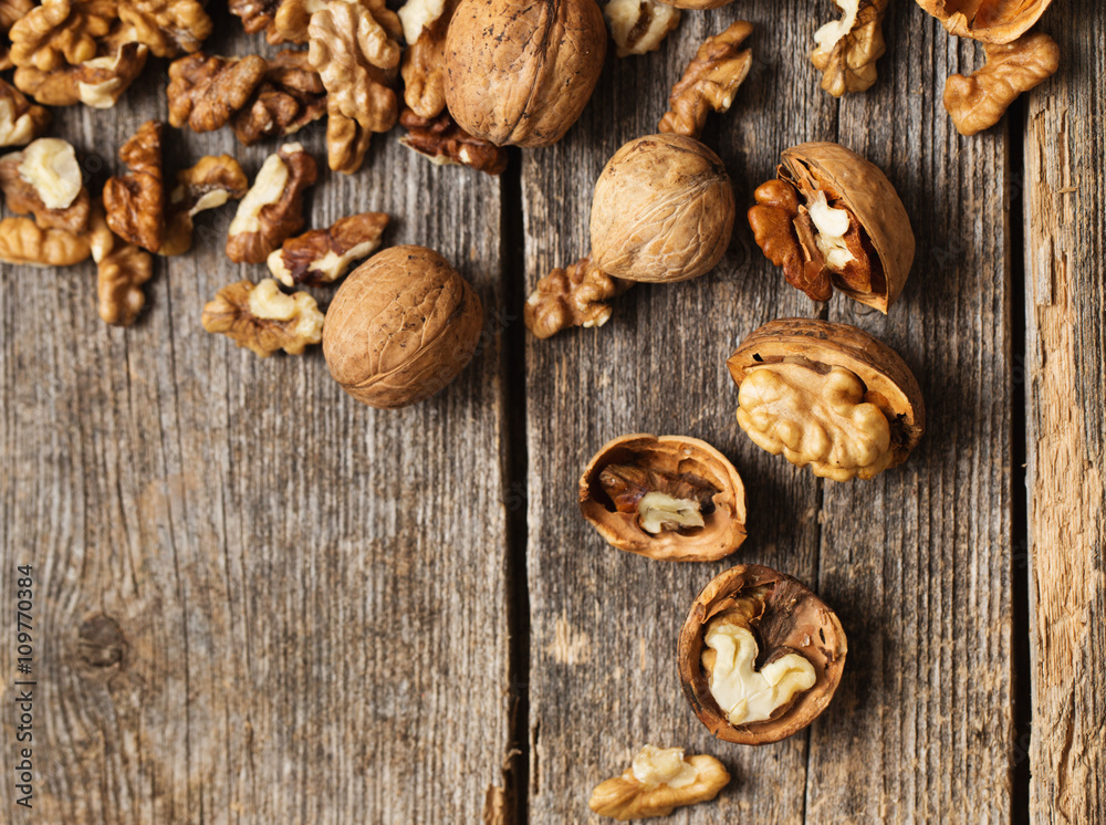 Walnut kernels and whole walnuts on rustic old wooden table Walnut kernels and whole walnuts on rustic old wooden table