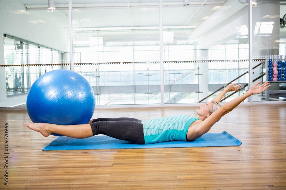 Fit blonde on mat holding fitness ball with legs Fit blonde on mat holding fitness ball with legs