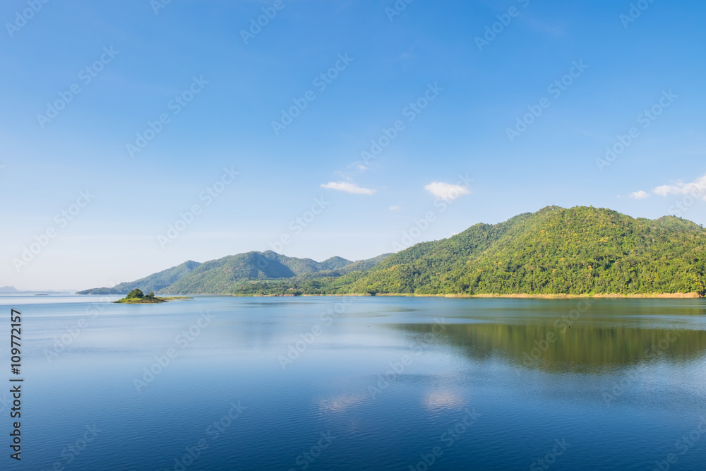 Blue sky reflection and mountain on dam at kanchanaburi