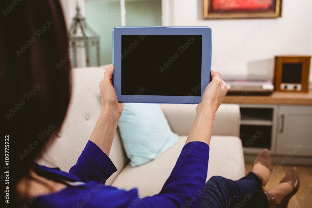 Rear view of woman holding digital tablet at home