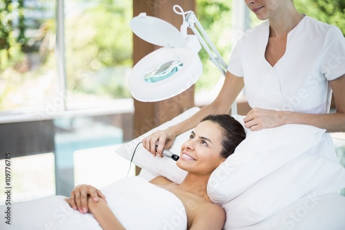 Smiling young woman receiving facial massage at spa