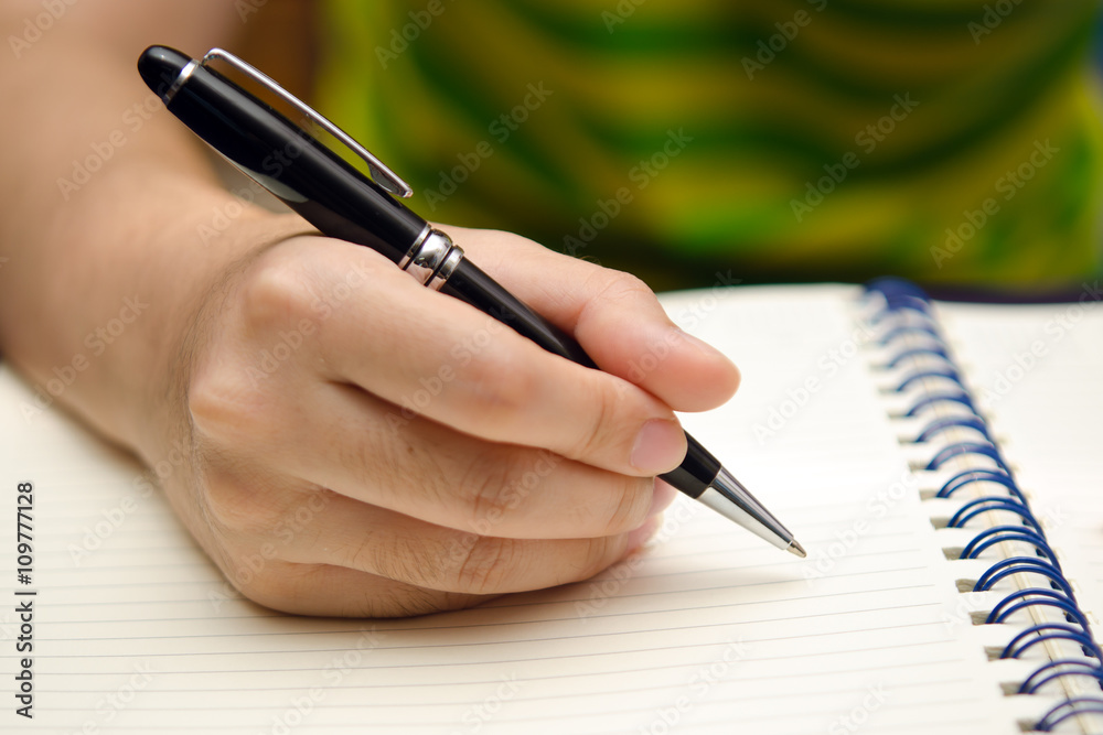 Hand hold a pen and write on a book