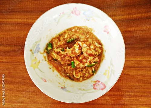 Nam Prik Kapi or shrimp paste with chilli sauce in a ceramic bowl on a wood table